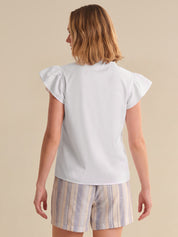 Woman wearing a white top and striped shorts on a beige background