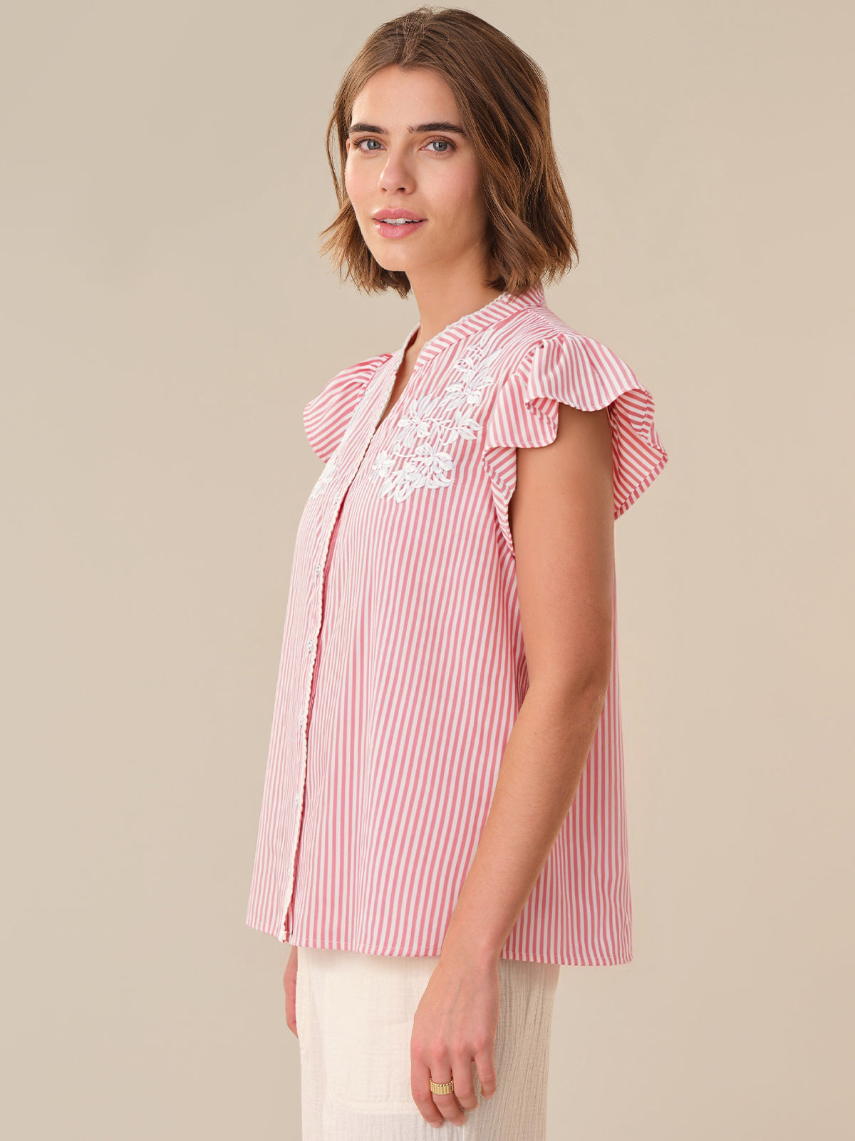 Woman wearing a red and white striped blouse with ruffled sleeves on a beige background