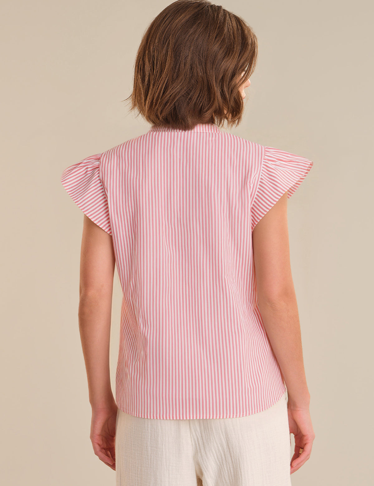 Woman wearing a red and white striped shirt with ruffled sleeves on a beige background