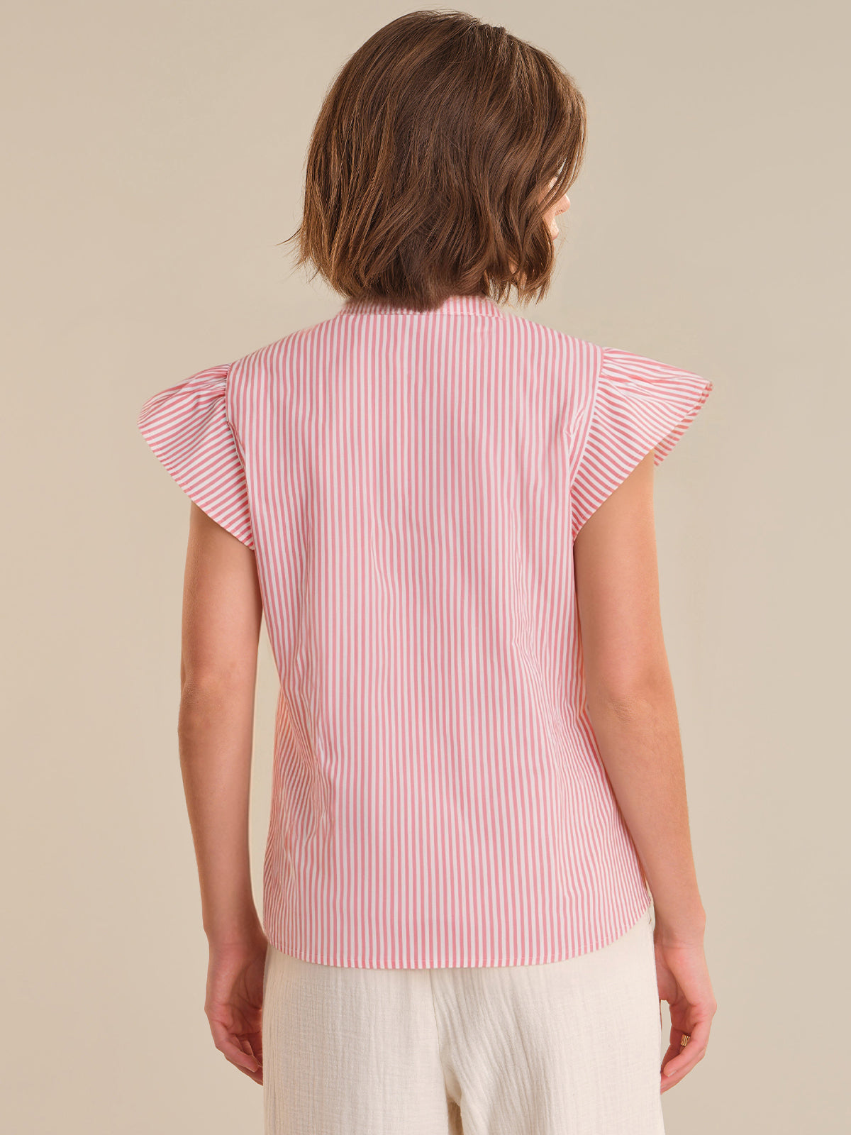 Woman wearing a red and white striped shirt with ruffled sleeves on a beige background