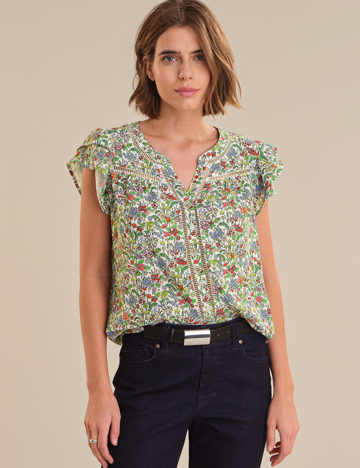 Woman wearing a colorful patterned blouse against a beige background