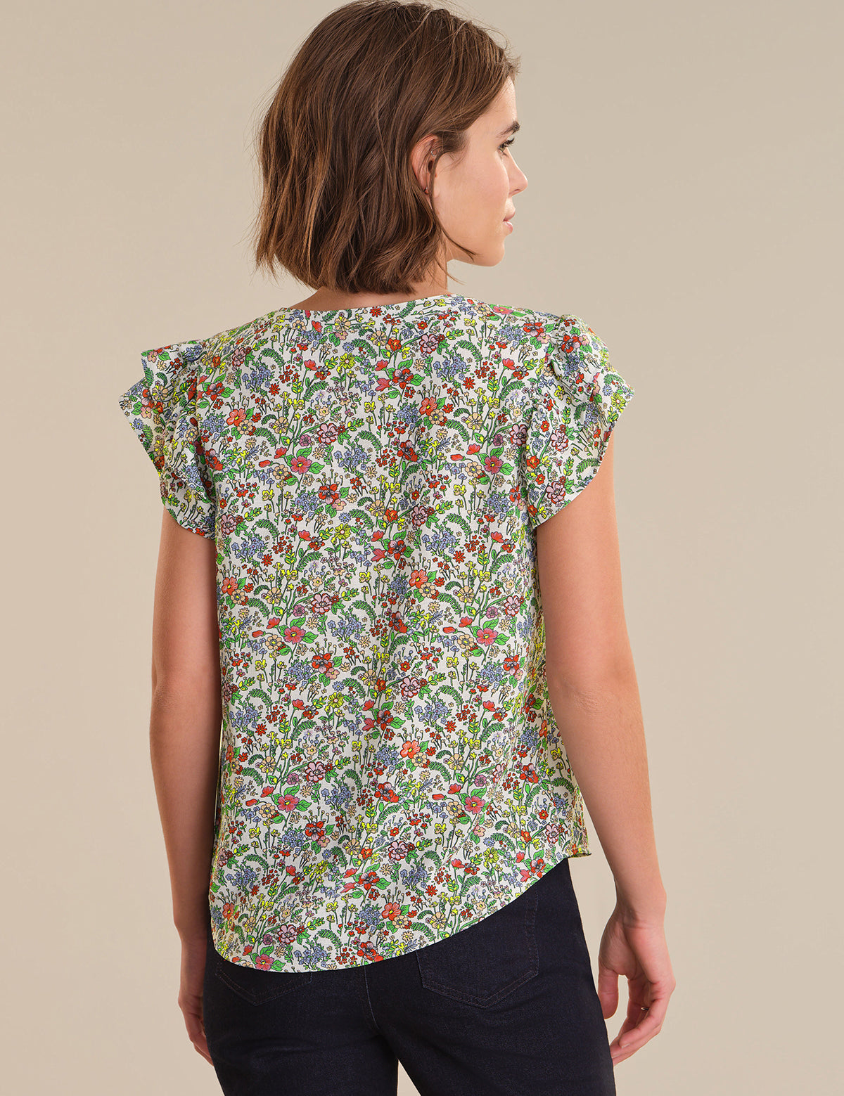 Woman wearing a floral blouse against a beige background