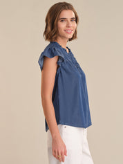 Woman wearing a blue denim top against a beige background