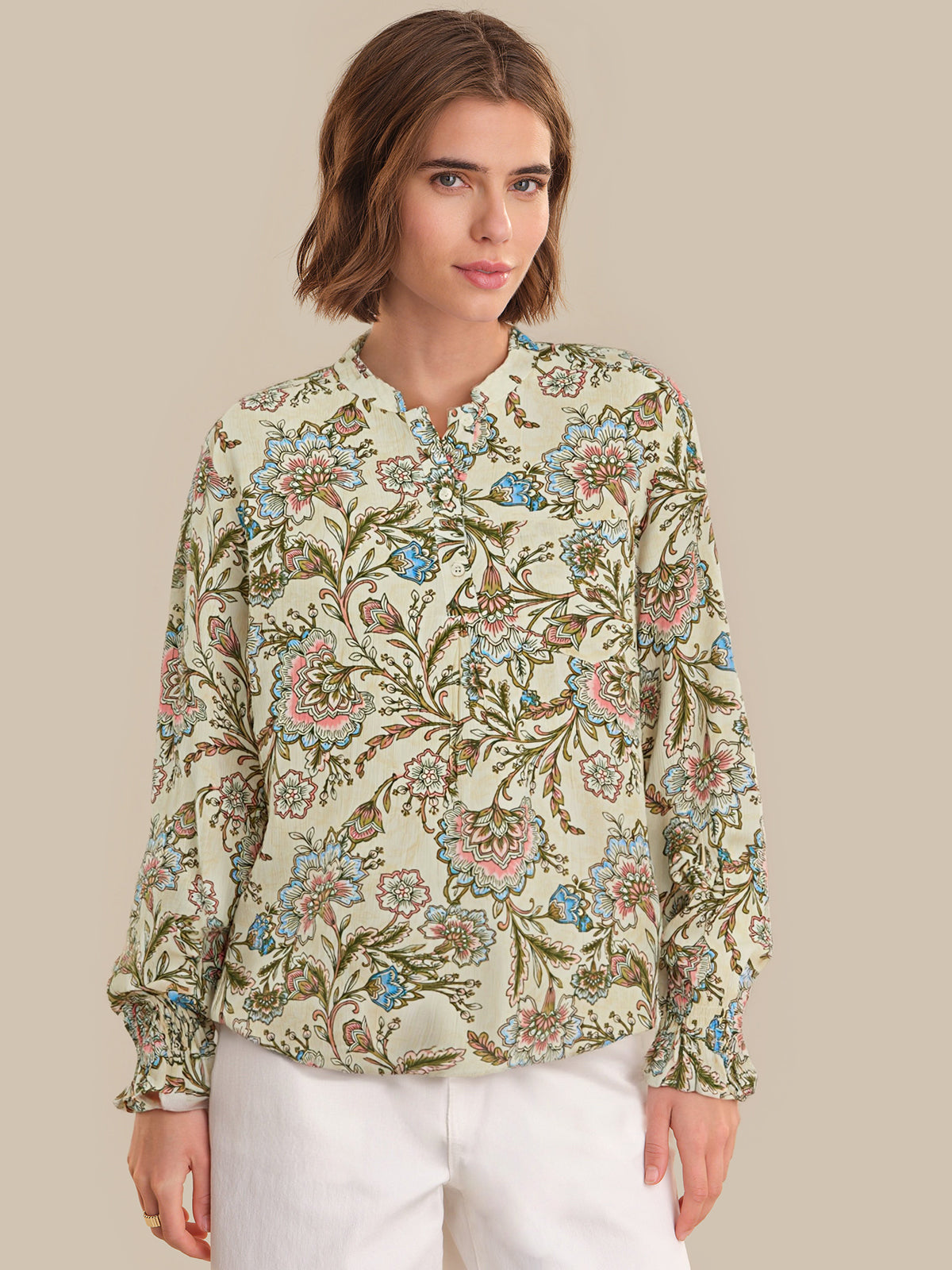 Woman wearing a floral patterned blouse against a beige background