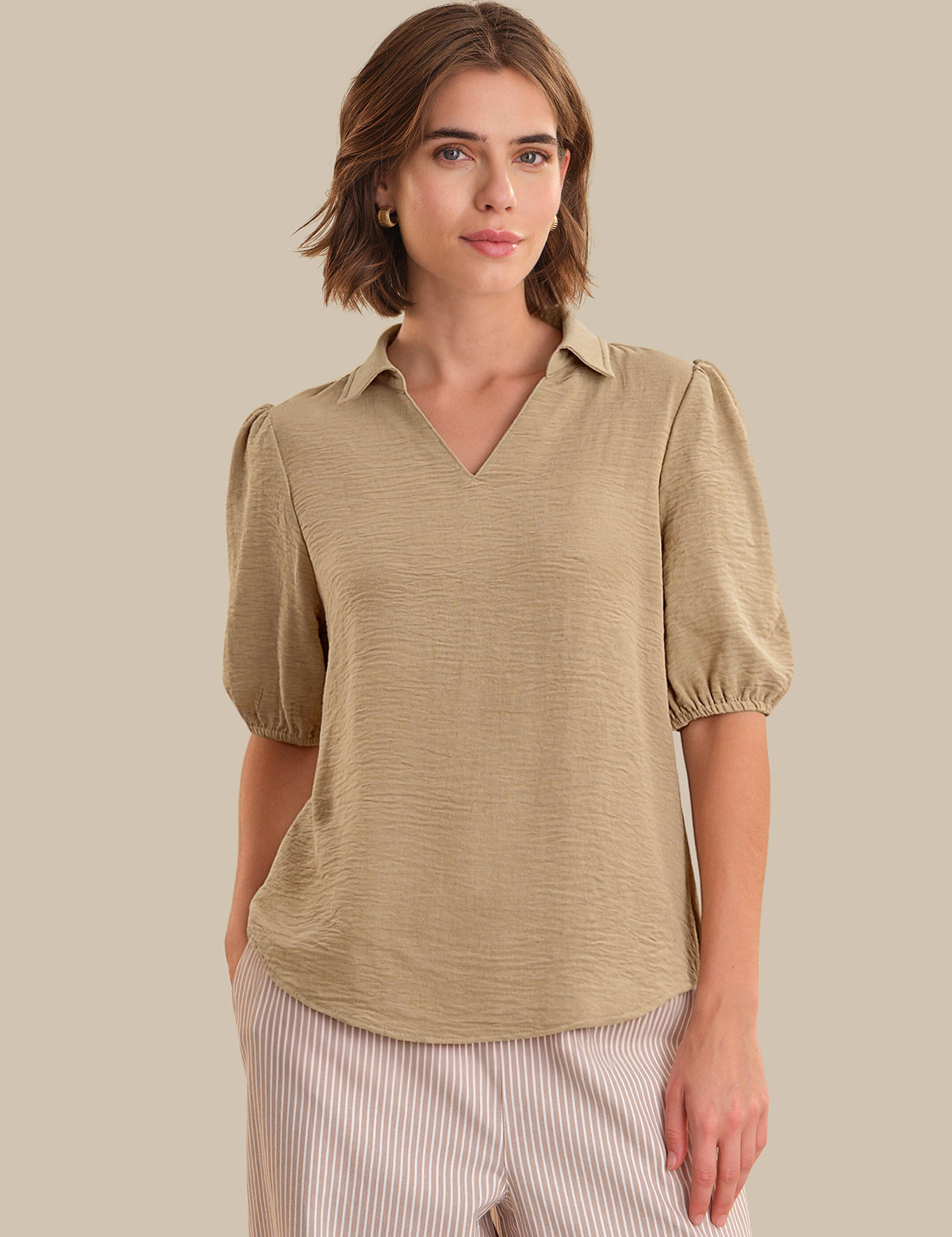 Woman wearing a beige blouse with puff sleeves against a beige background