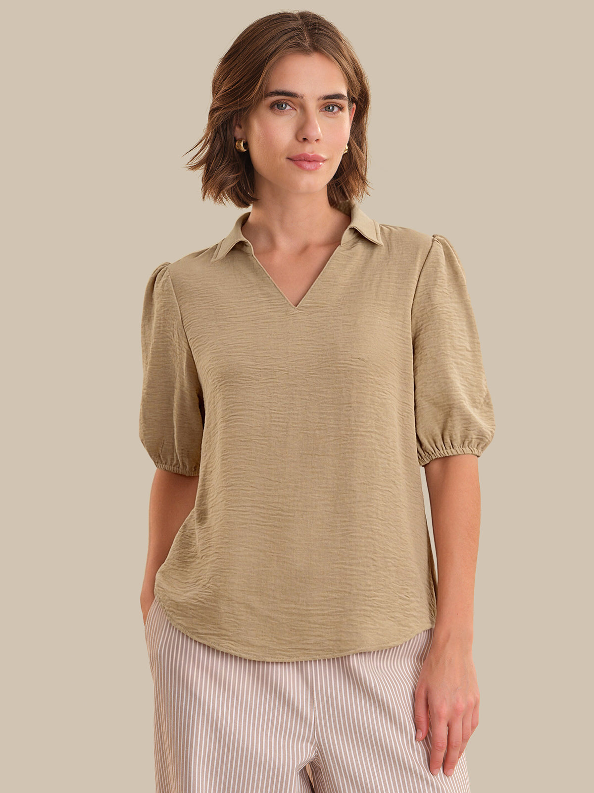 Woman wearing a beige blouse with puff sleeves against a beige background