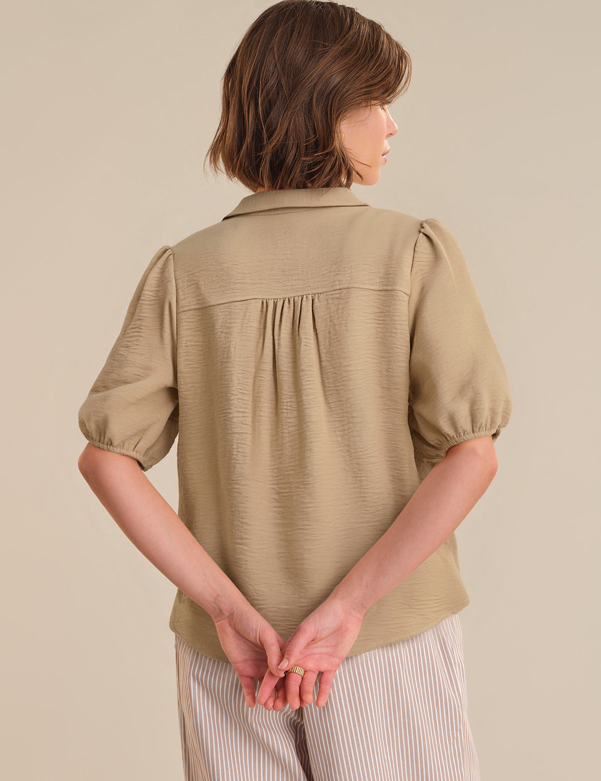 Woman wearing a beige textured blouse against a plain background
