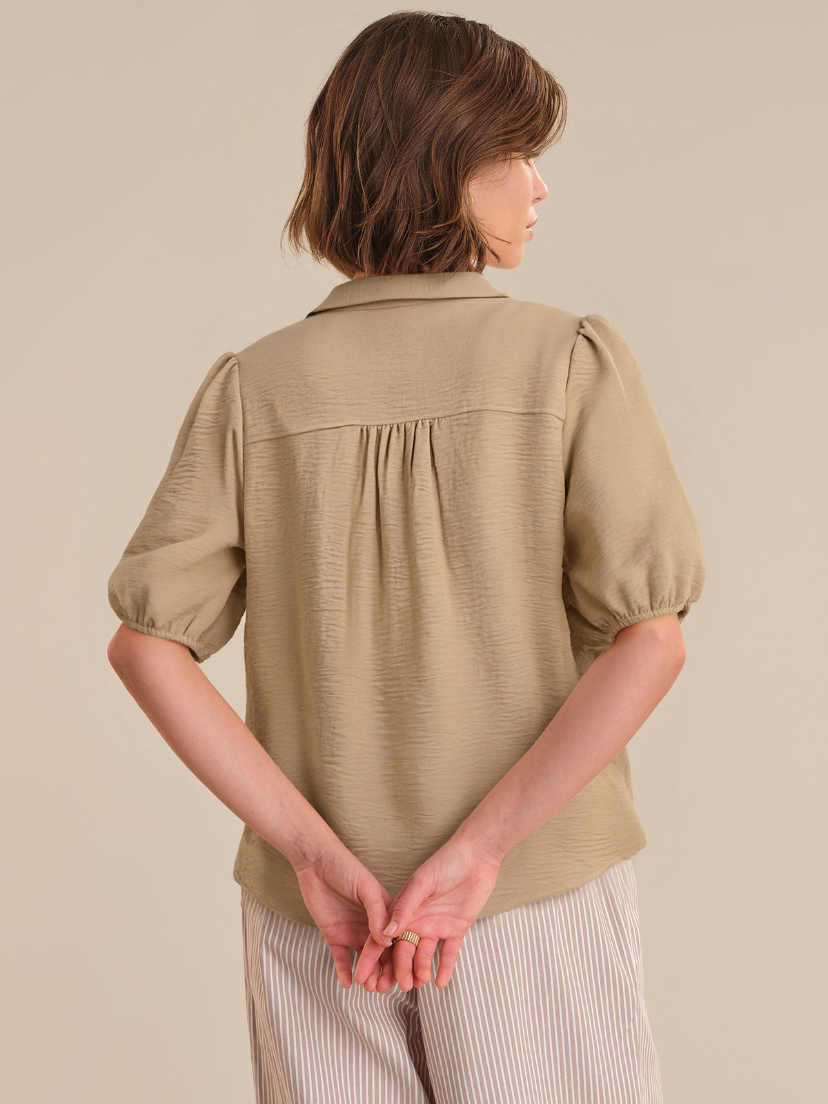 Woman wearing a beige textured blouse against a plain background