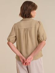 Woman wearing a beige textured blouse against a plain background