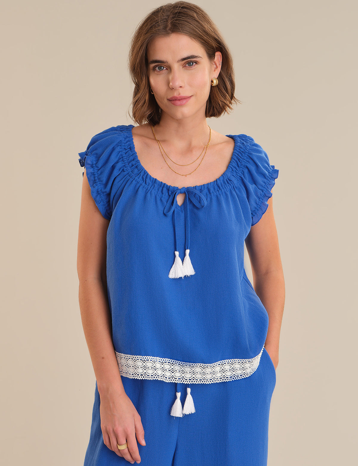 Woman wearing a blue top with white details on a beige background