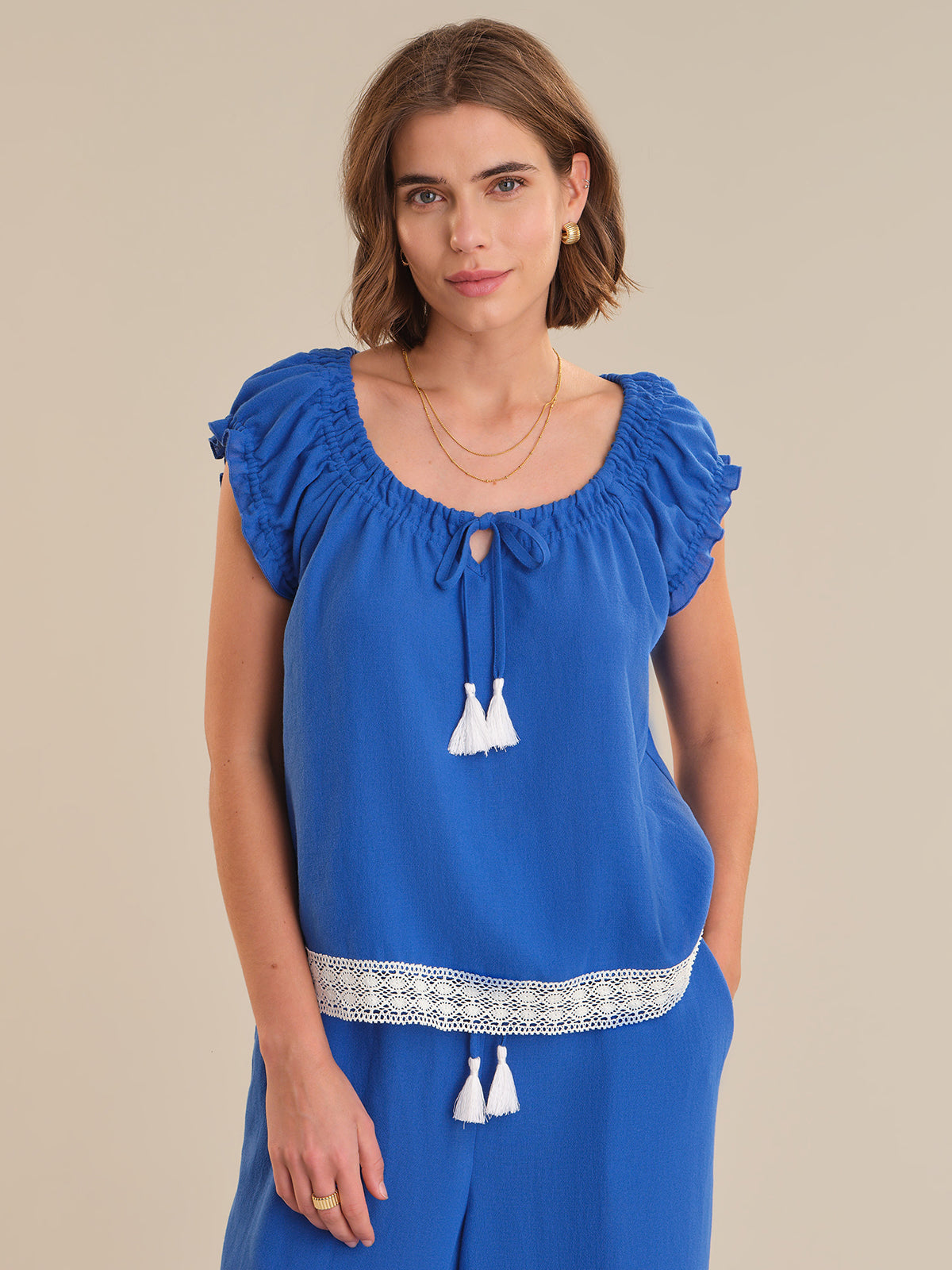 Woman wearing a blue top with white details on a beige background