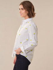 Woman wearing a white blouse with yellow patterns on a beige background