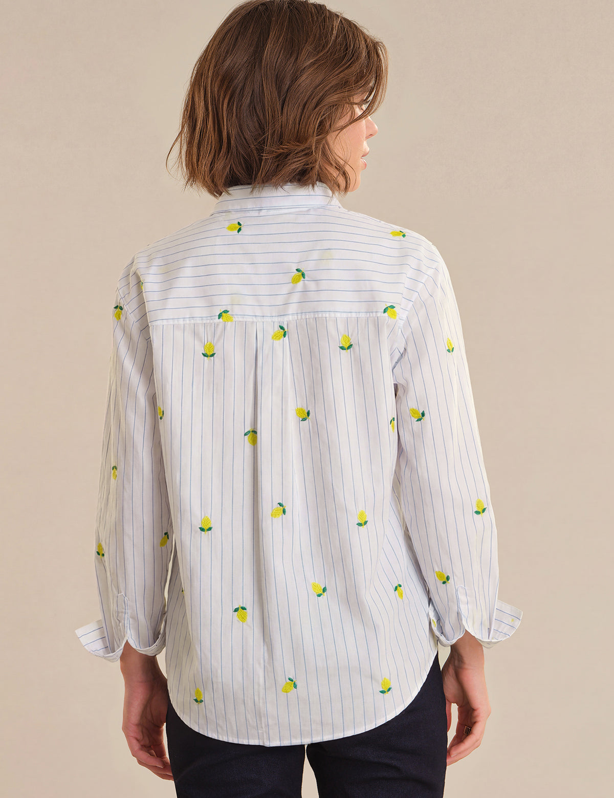 Person wearing a white shirt with lemon pattern on a beige background