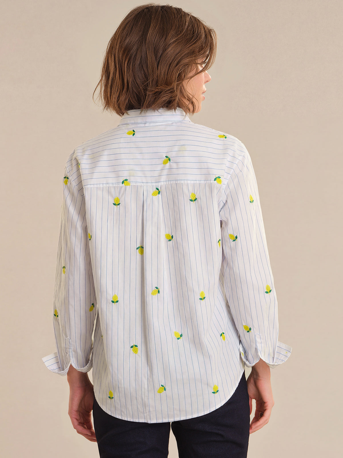 Person wearing a white shirt with lemon pattern on a beige background