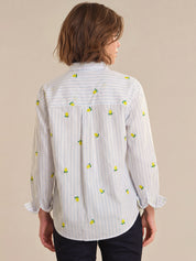 Person wearing a white shirt with lemon pattern on a beige background