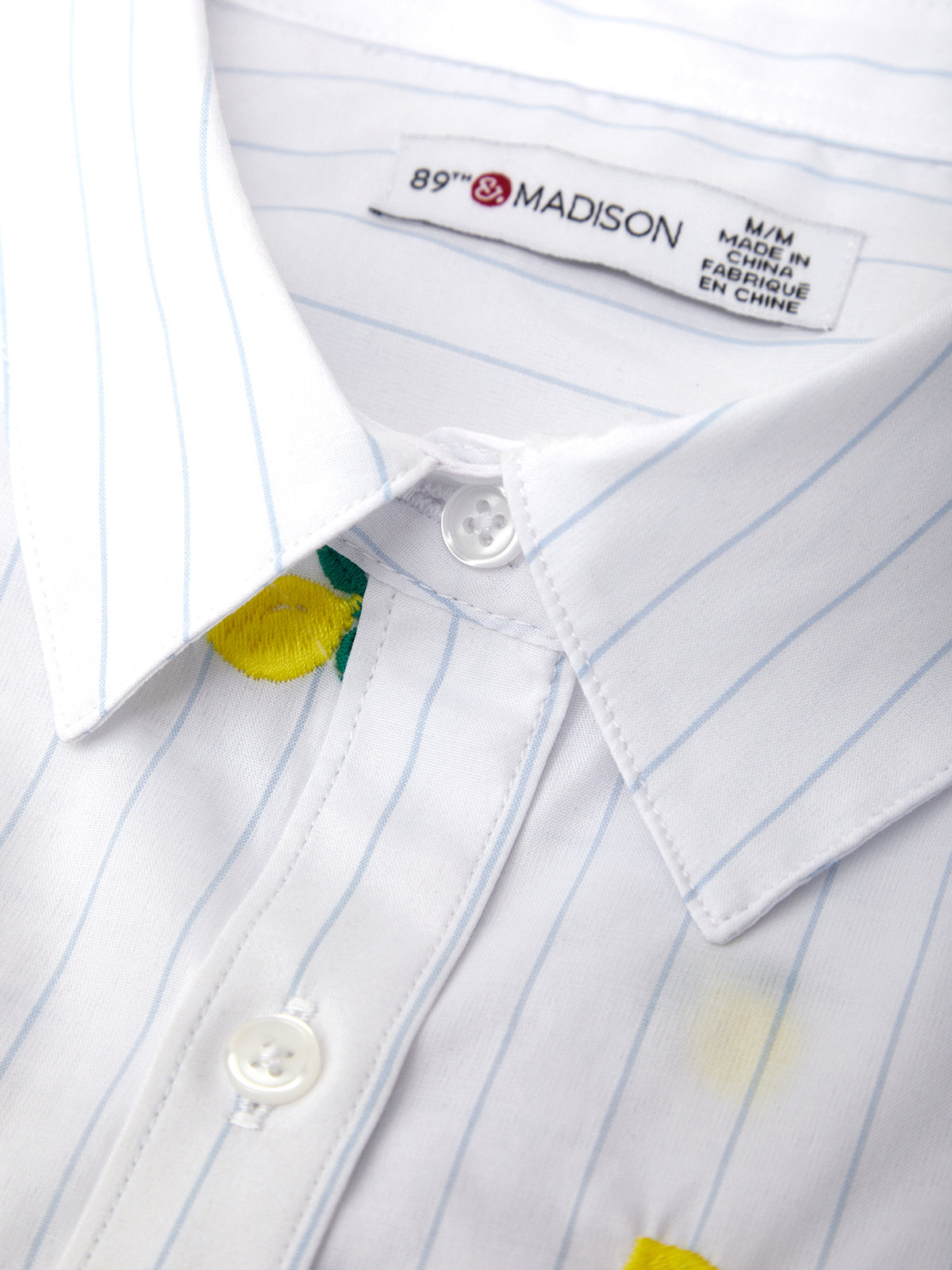 Close-up of a white shirt with blue pinstripes and a 'Madison' label.