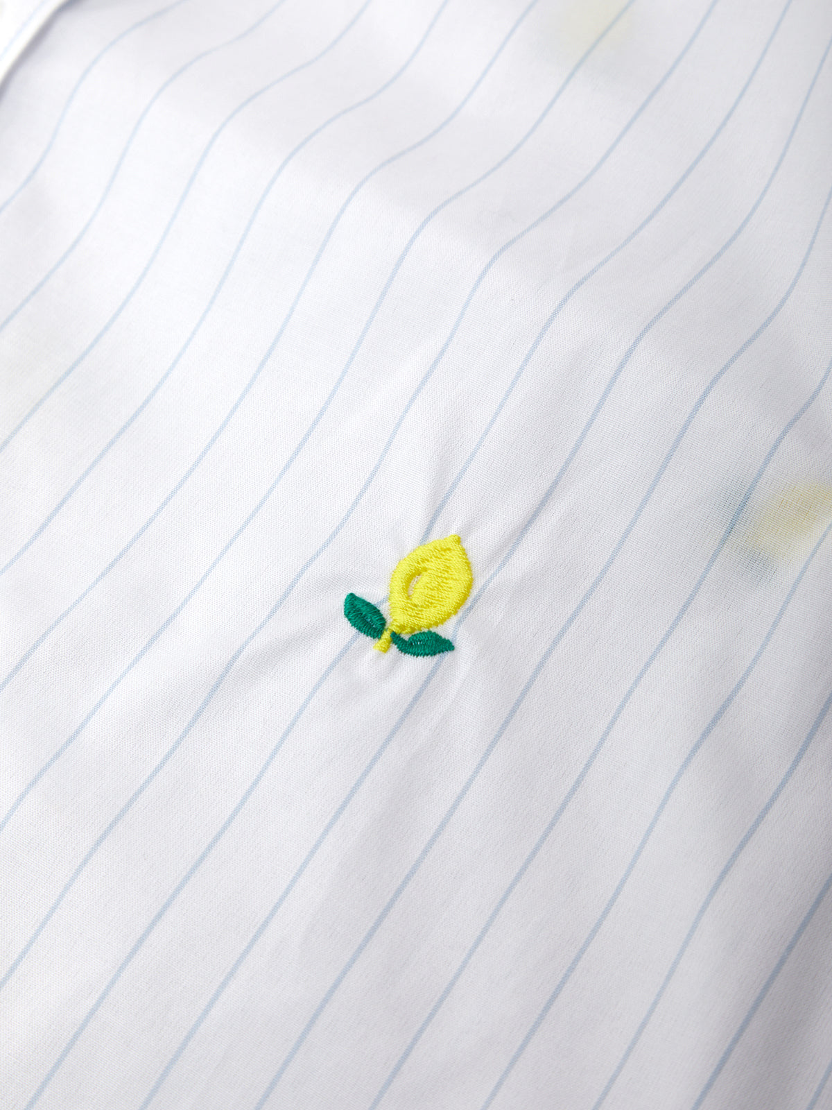 Embroidered lemon design on a white shirt with blue pinstripes