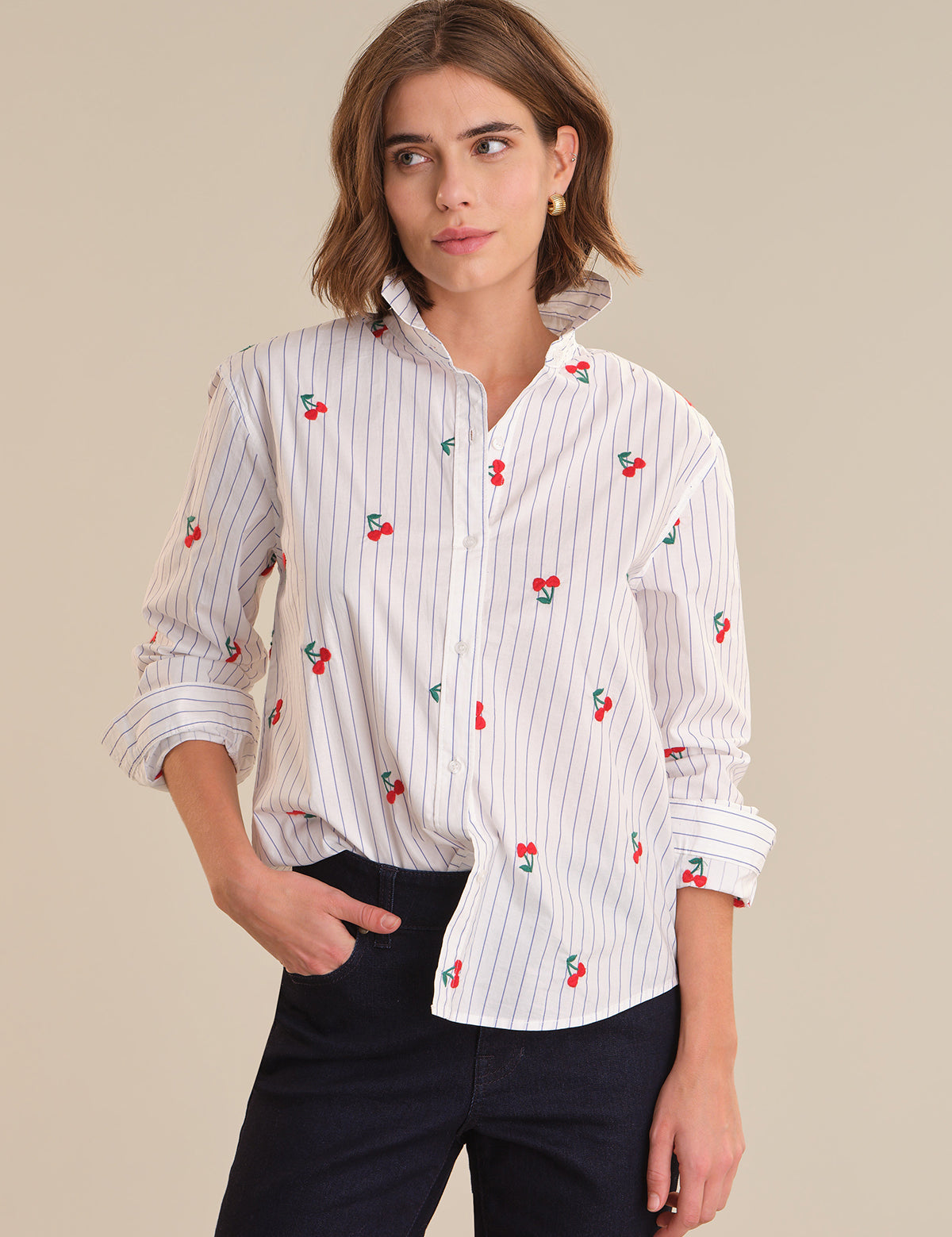 Woman wearing a white shirt with red cherry patterns on a beige background