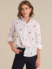 Woman wearing a white shirt with red cherry patterns on a beige background