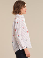 Woman wearing a white blouse with red floral patterns on a beige background