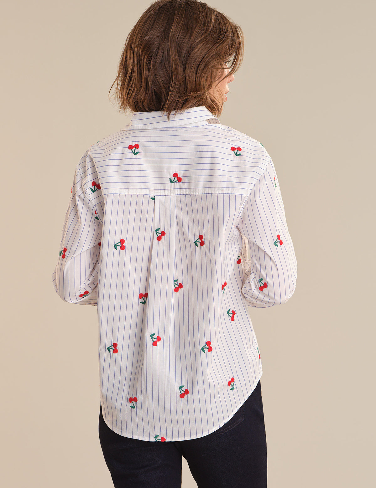 Woman wearing a white shirt with red cherry patterns on a beige background