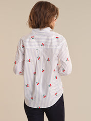 Woman wearing a white shirt with red cherry patterns on a beige background