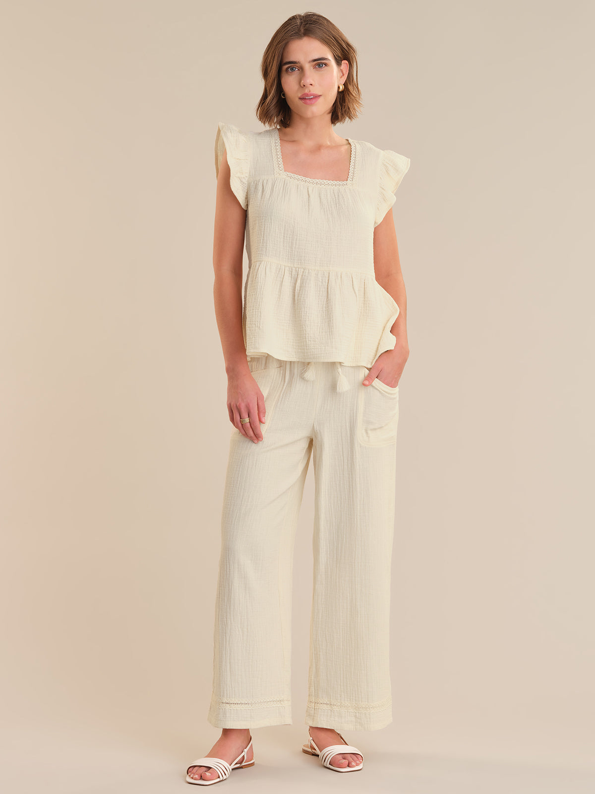 Woman wearing a cream-colored outfit with a plain background