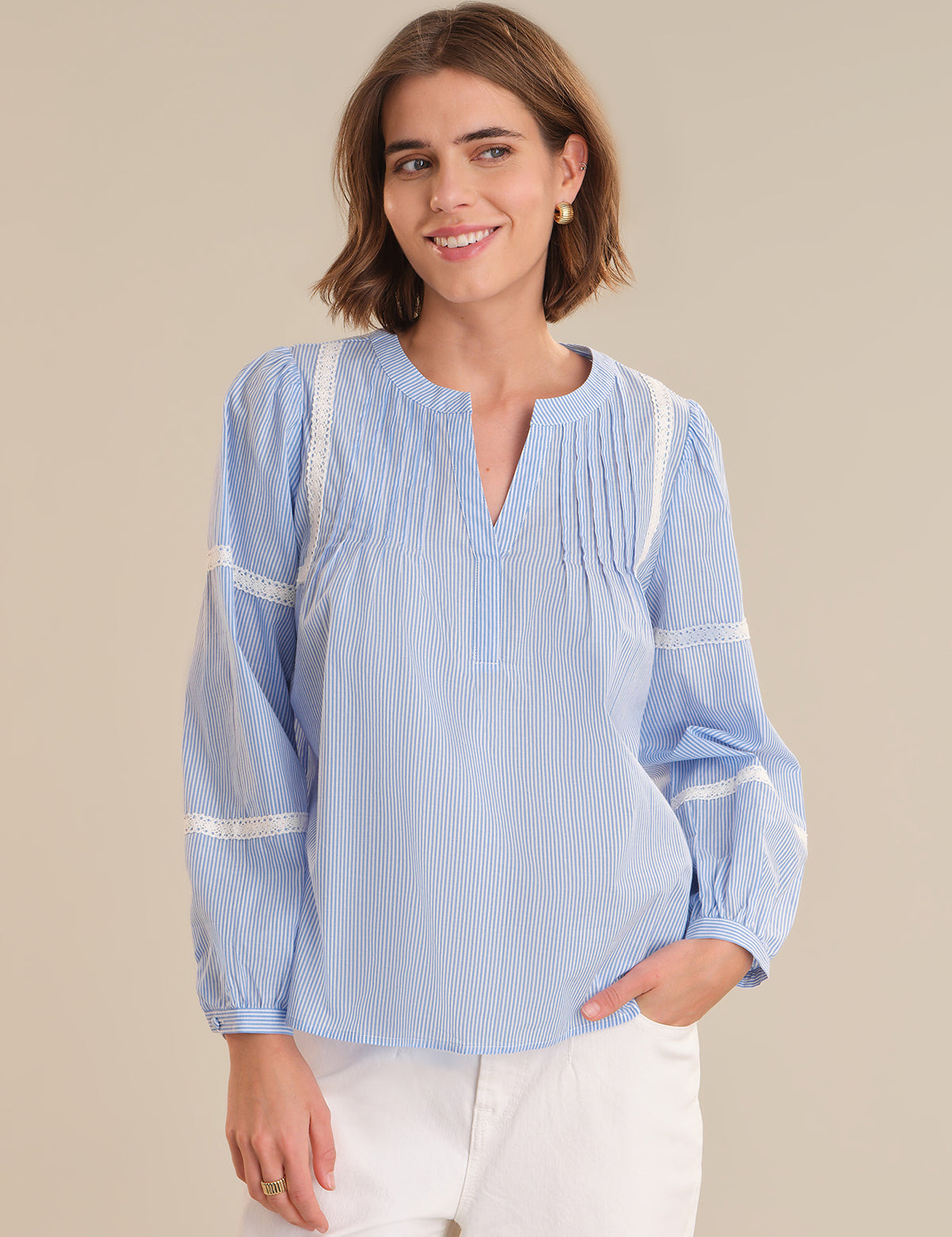 Woman wearing a light blue striped blouse with white trim on a beige background