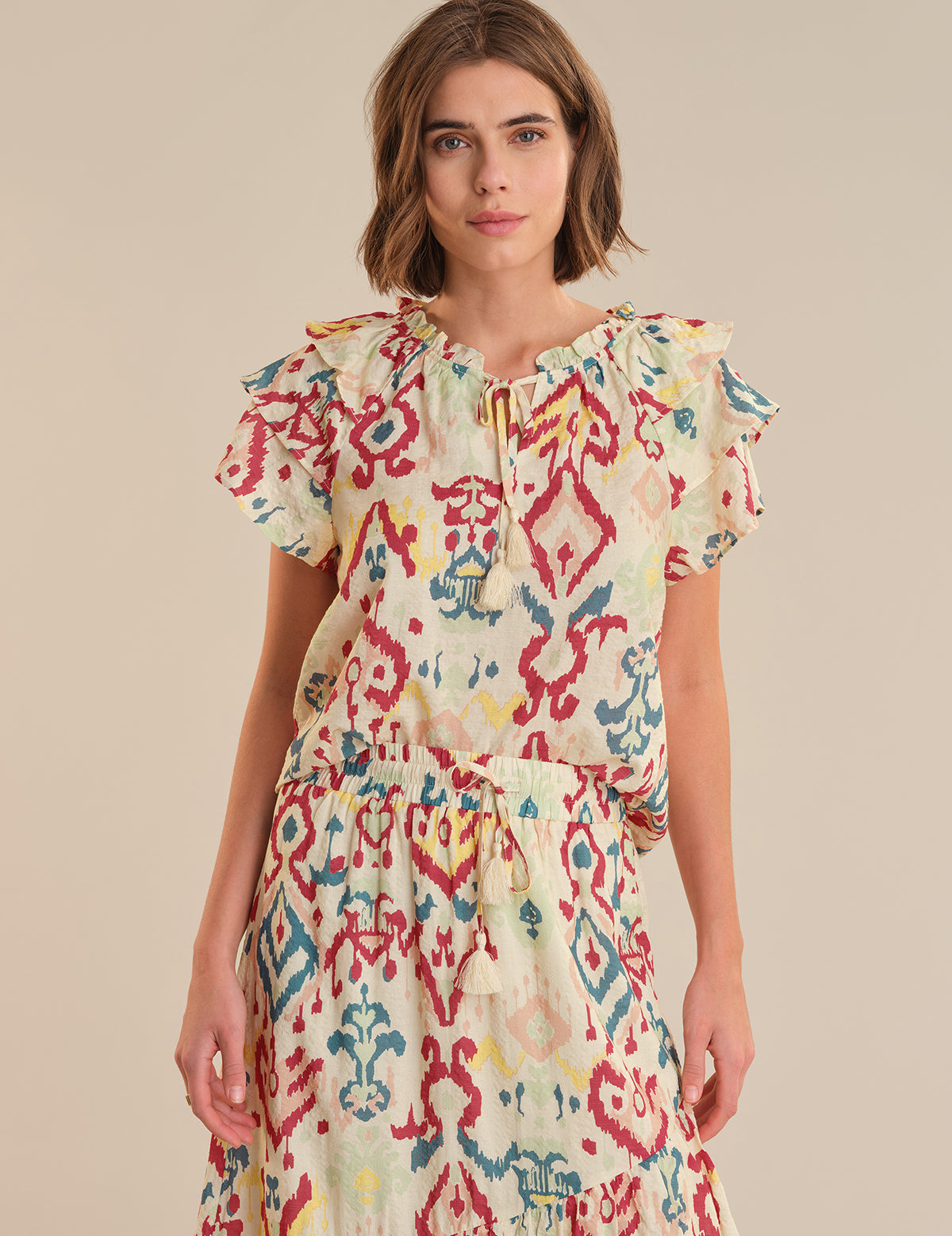 Woman wearing a colorful patterned dress on a beige background