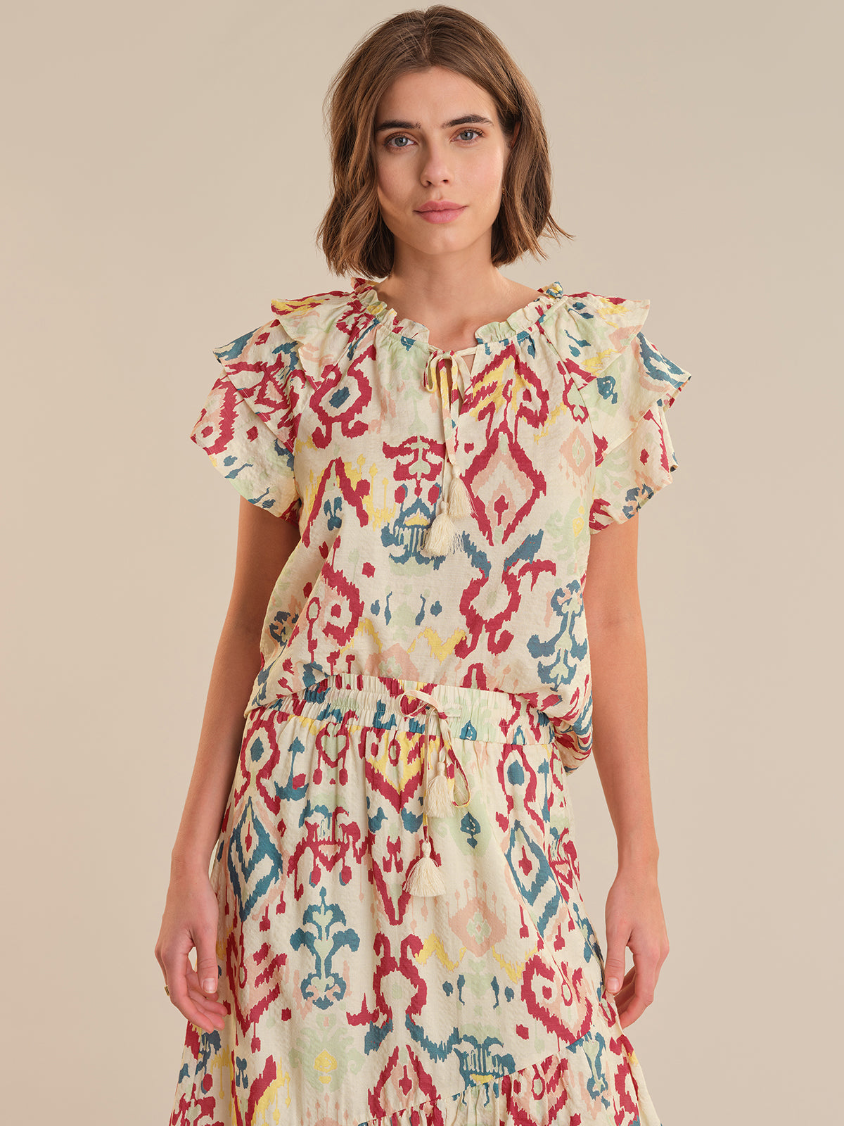 Woman wearing a colorful patterned dress on a beige background