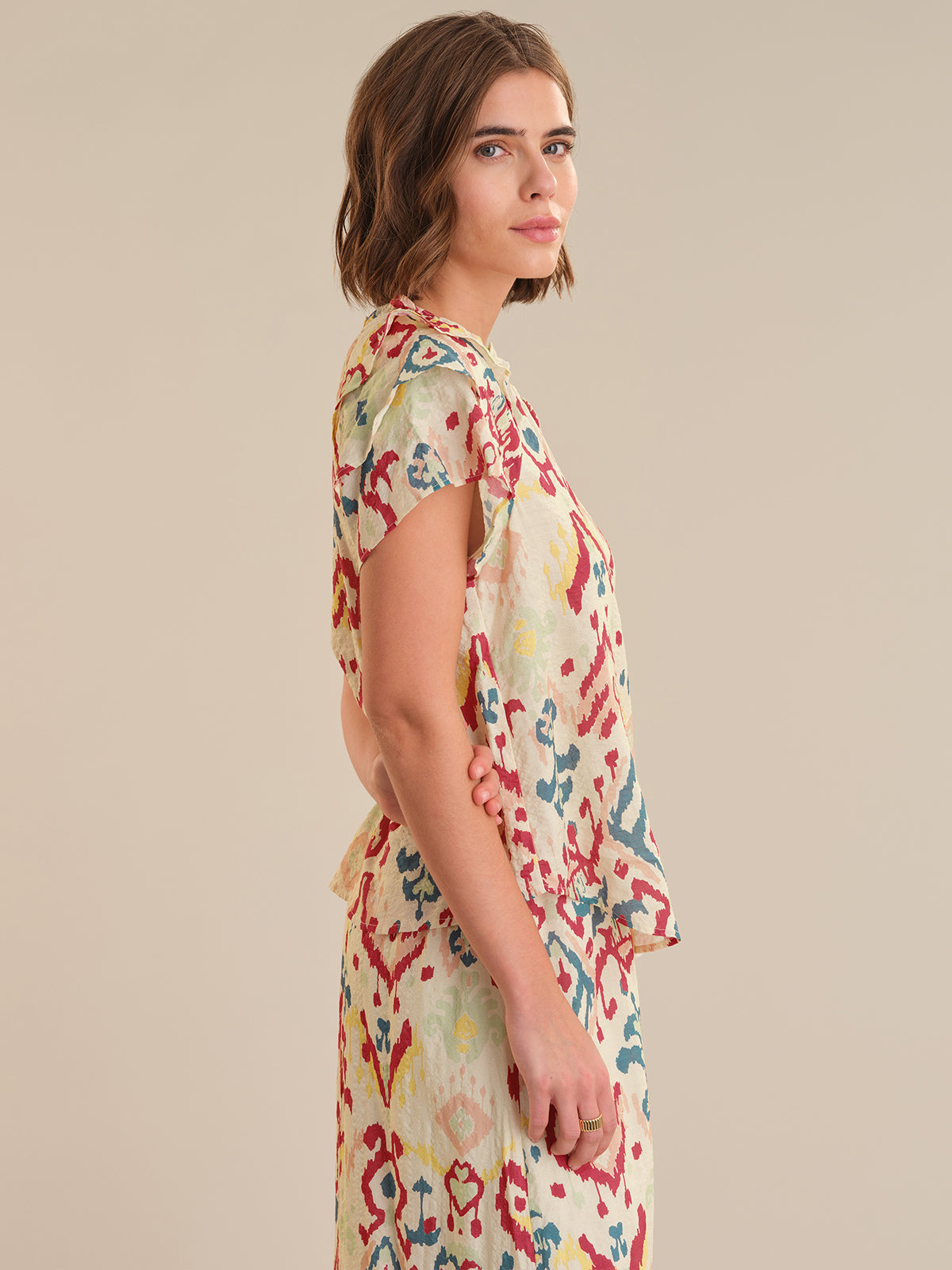 Woman wearing a colorful floral dress against a beige background