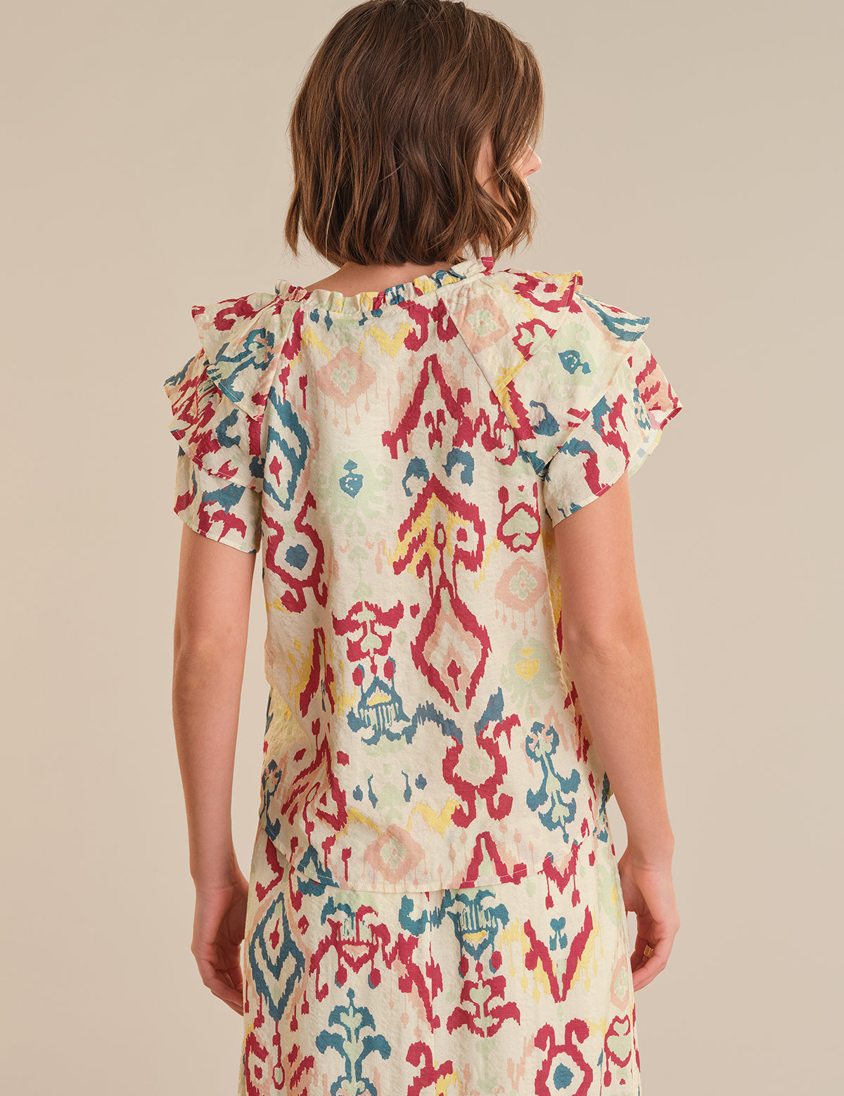 Woman wearing a colorful patterned dress on a beige background