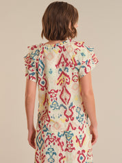 Woman wearing a colorful patterned dress on a beige background