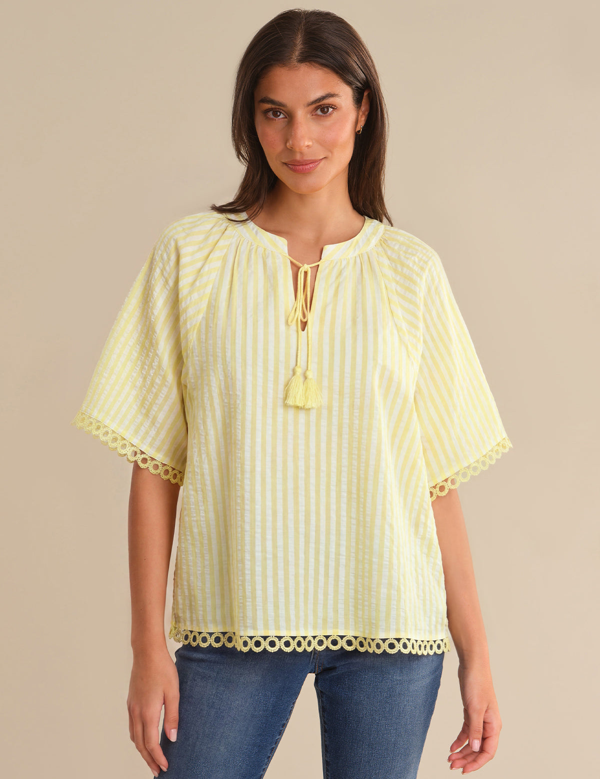 Woman wearing a yellow striped blouse with a beige background
