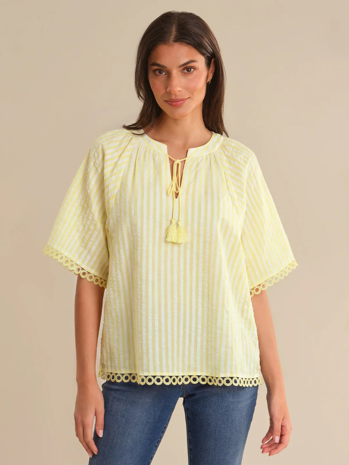 Woman wearing a yellow striped blouse with a beige background