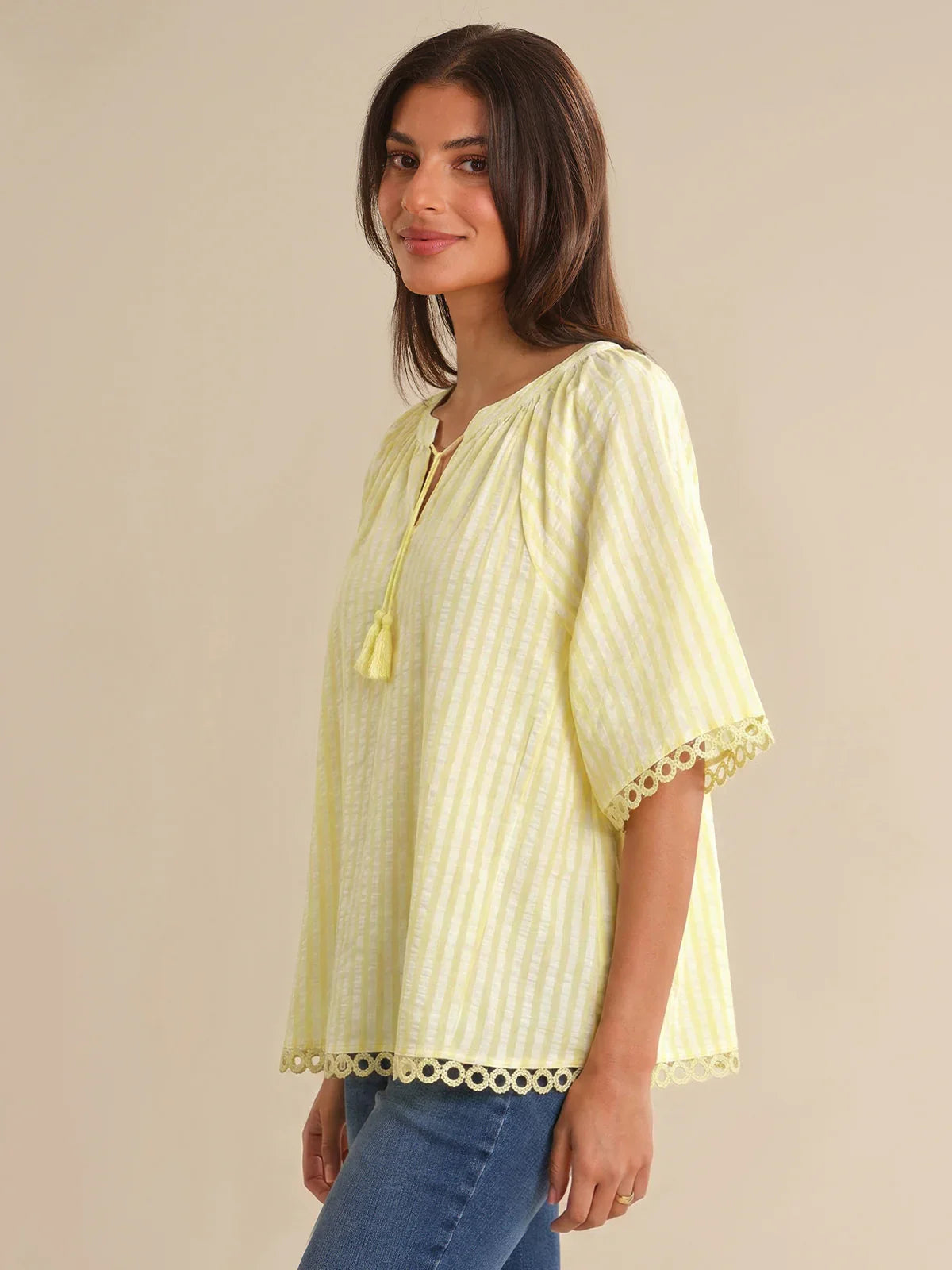 Woman wearing a light yellow blouse with a beige background