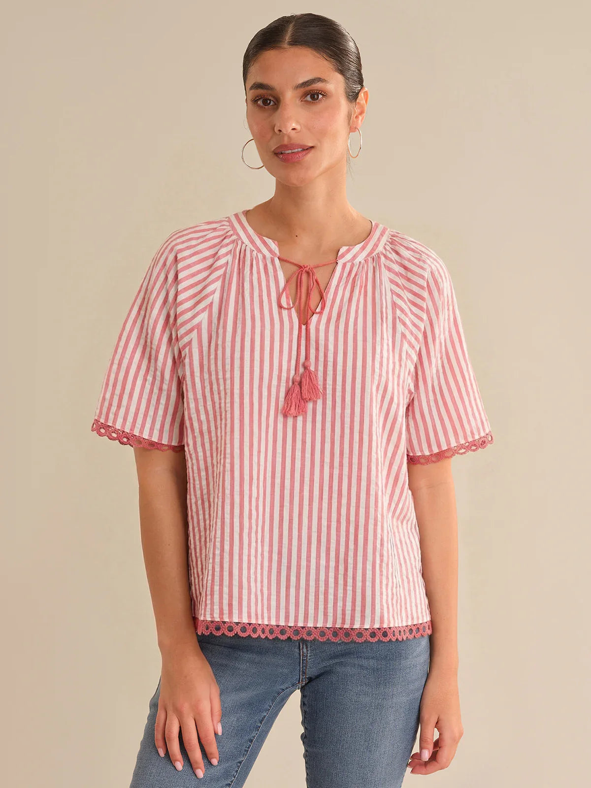 Woman wearing a red and white striped blouse with a beige background