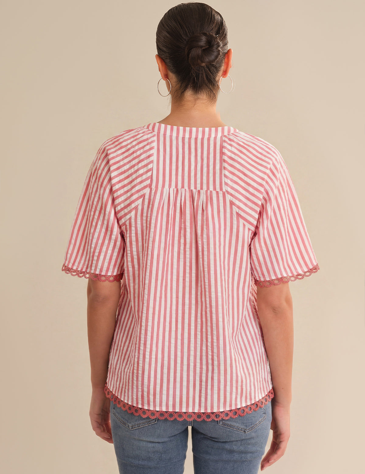 Person wearing a red and white striped shirt with scalloped hem on a beige background
