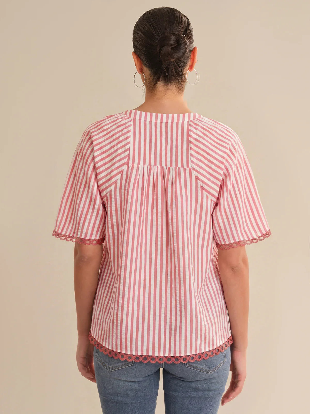 Person wearing a red and white striped shirt with scalloped hem on a beige background