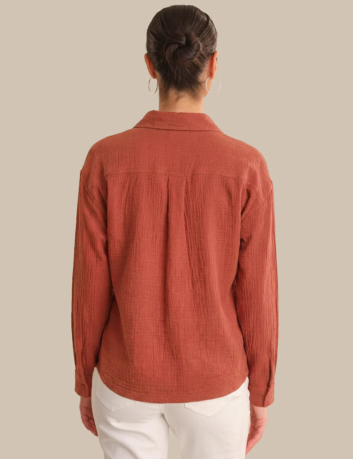 Person wearing a rust-colored corduroy shirt against a beige background