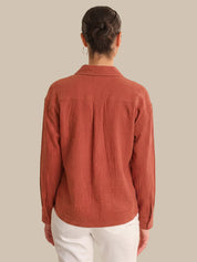 Person wearing a rust-colored corduroy shirt against a beige background