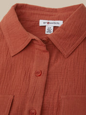 Close-up of a rust-colored shirt with a brand label on a beige background
