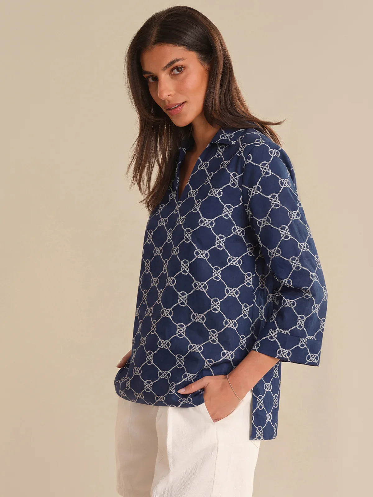 Woman wearing a navy blue patterned shirt against a beige background