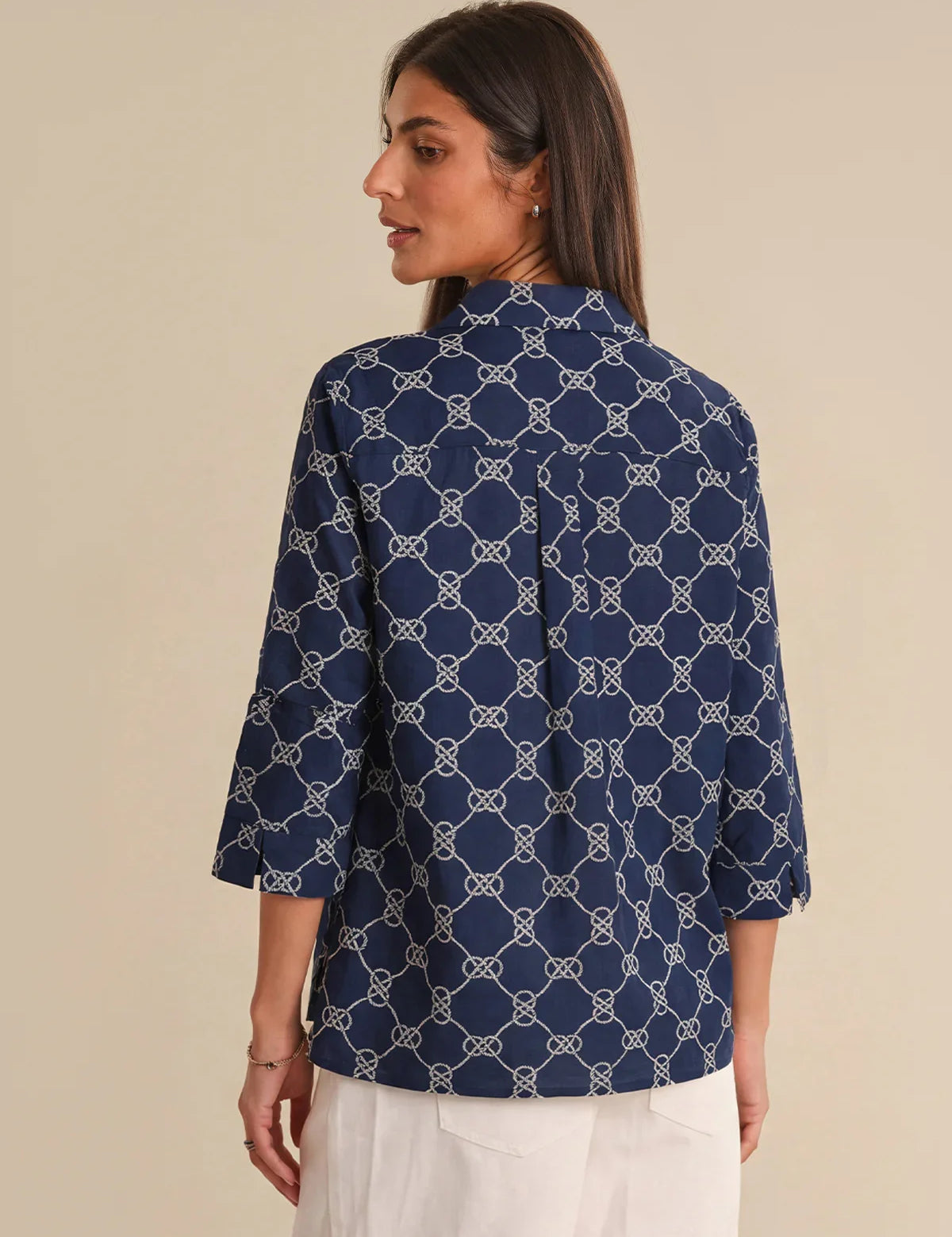 Woman wearing a navy blue patterned shirt against a beige background