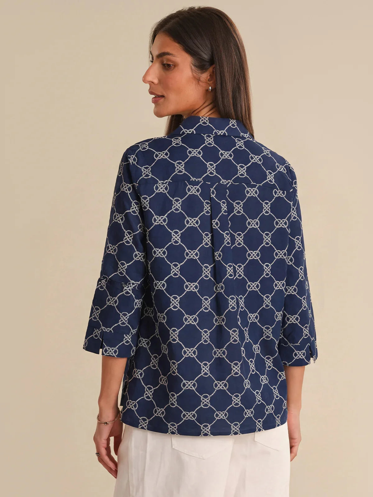Woman wearing a navy blue patterned shirt against a beige background