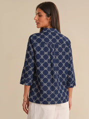 Woman wearing a navy blue patterned shirt against a beige background