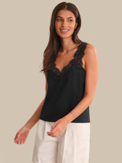 Woman wearing a black lace-trimmed top against a beige background