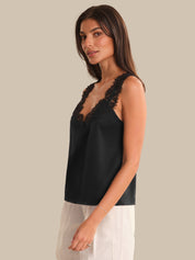 Woman wearing a black lace-trimmed top against a neutral background