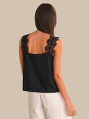 Black sleeveless top with lace details on a plain background
