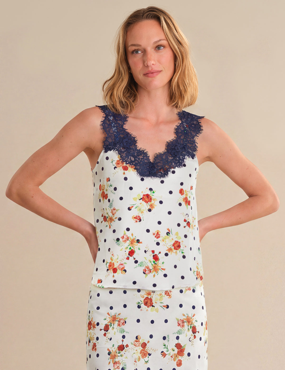 Woman wearing a sleeveless top with floral and polka dot patterns on a beige background
